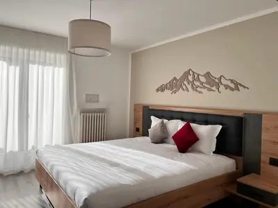a bedroom with a large bed with red and white pillows at Hotel Rododendro Val di Fassa in Campitello di Fassa