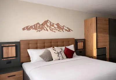 a bedroom with a large bed with mountains on the wall at Hotel Rododendro Val di Fassa in Campitello di Fassa