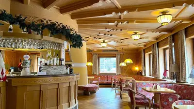 a restaurant with a bar and tables and chairs at Hotel Rododendro Val di Fassa in Campitello di Fassa