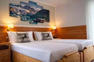 a bedroom with two beds and a painting on the wall at Hotel Rododendro Val di Fassa in Campitello di Fassa
