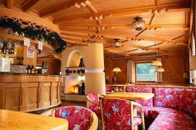 a restaurant with red chairs and a bar at Hotel Rododendro Val di Fassa in Campitello di Fassa