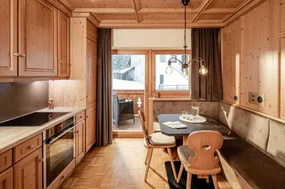 a kitchen with a table and chairs in a room at Suites Hotel Garden in Selva di Val Gardena