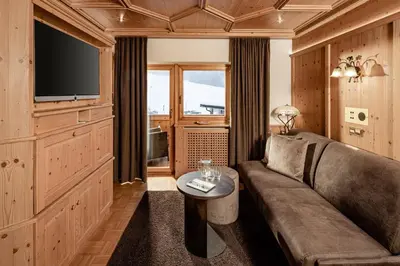 a living room with a couch and a television at Suites Hotel Garden in Selva di Val Gardena