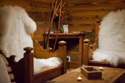 a room with a table and white fur covered chairs at Residence Merk in Selva di Val Gardena