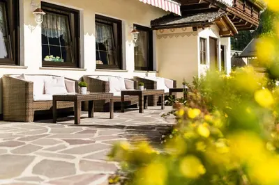 a patio with wicker chairs and tables on a building at Romantik & Family Hotel Gardenia***S in Selva di Val Gardena