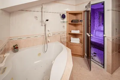 a white tub in a bathroom with a purple door at Romantik & Family Hotel Gardenia***S in Selva di Val Gardena