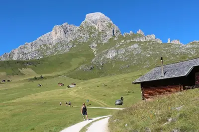 a man walking down a path in front of a mountain at Appartamenti Ciasa Linda in San Martino in Badia