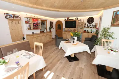 a dining room with two tables and a kitchen at Appartamenti Ciasa Linda in San Martino in Badia
