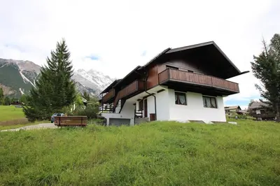 a small house with a black roof on a green field at Overlooking the Dolomites in Cortina dʼAmpezzo