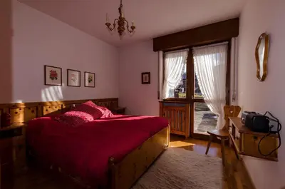 a bedroom with a bed with red sheets and a window at Overlooking the Dolomites in Cortina dʼAmpezzo