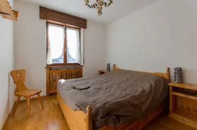 a bedroom with a bed and a chair and a window at Overlooking the Dolomites in Cortina dʼAmpezzo
