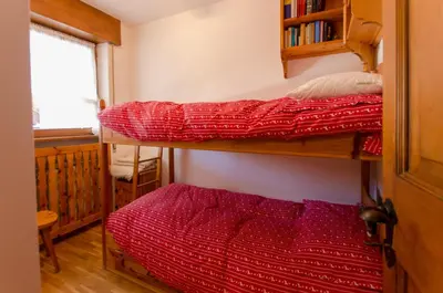 a bedroom with two bunk beds and a window at Overlooking the Dolomites in Cortina dʼAmpezzo