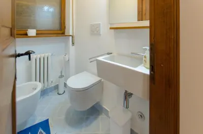 a white bathroom with a sink and a toilet at Overlooking the Dolomites in Cortina dʼAmpezzo