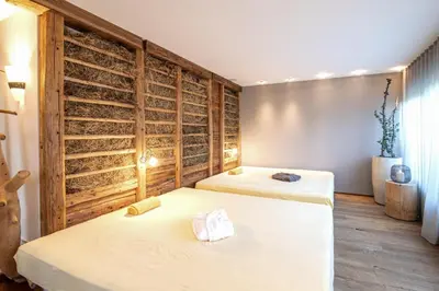 two beds in a room with wooden walls at Alpin Hotel Gudrun in Colle Isarco