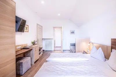 a large bedroom with two beds and a television at Alpin Hotel Gudrun in Colle Isarco
