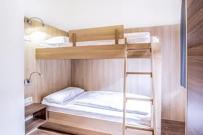 a bunk bed in a small room with a ladder at Alpin Hotel Gudrun in Colle Isarco