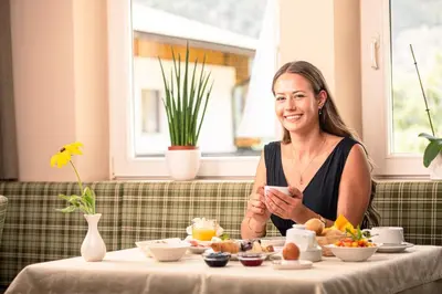 a woman sitting at a table with food at Hotel Mair in Campo Tures