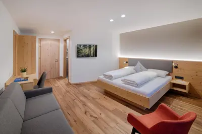a hotel room with a bed and a couch at Hotel Mair in Campo Tures