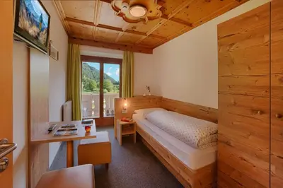 a bedroom with a bed and a desk and a window at Hotel Mair in Campo Tures
