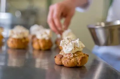 a person is sprinkling ice cream on a pastry at Hotel Alla Posta - Famiglia Pra dal 1866 a Caprile in Alleghe
