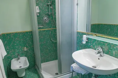 a green tiled bathroom with a sink and a shower at Hotel Alla Posta - Famiglia Pra dal 1866 a Caprile in Alleghe