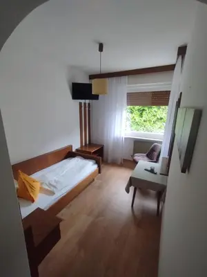 a bedroom with a bed and a chair and a window at Garni Weingut in Merano