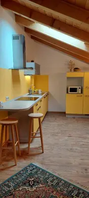 a kitchen with yellow cabinets and a sink and stool at Haus Traudi in Nova Ponente