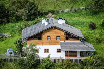 a wooden house with a roof on a hill at Haus Traudi in Nova Ponente