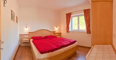a bedroom with a bed with a red blanket at Unterstoan Hof in Termeno