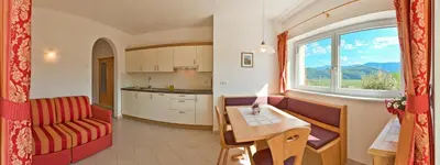 a kitchen and a living room with a table and a window at Unterstoan Hof in Termeno