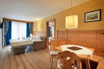 a hotel room with a bed and a table and chairs at Mountain Hotel Mezdì in Colfosco