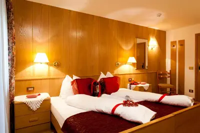 a hotel room with two beds with red and white pillows at Mountain Hotel Mezdì in Colfosco
