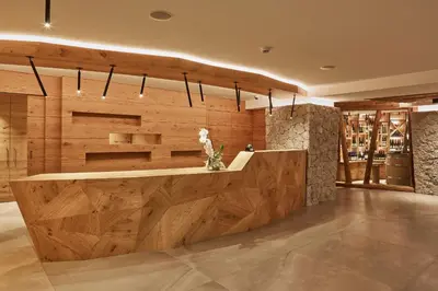 a lobby with a wooden wall with a vase of flowers at Mountain Hotel Mezdì in Colfosco