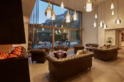 a living room with couches and chairs and a large window at Mountain Hotel Mezdì in Colfosco