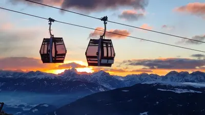 a pair of ski lifts in front of a mountain at Tratterhof Mountain Sky Hotel in Maranza