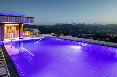 a swimming pool with purple lighting on top of a house at Tratterhof Mountain Sky Hotel in Maranza