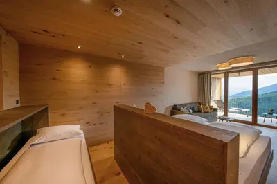 a room with two beds and a large window at Tratterhof Mountain Sky Hotel in Maranza