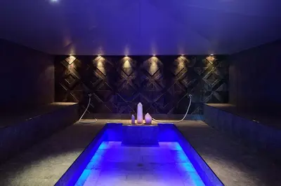 a swimming pool with purple lights in a room at Tratterhof Mountain Sky Hotel in Maranza