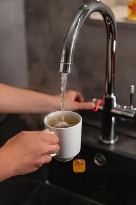 a person is drinking coffee from a cup under a sink at Hotel Brenner - Stop & Go in Vipiteno