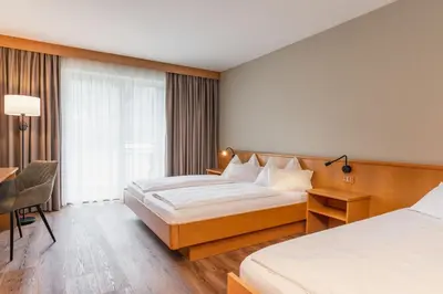 a hotel room with two beds and a desk at Hotel Brenner - Stop & Go in Vipiteno