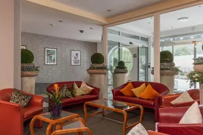 a living room with red chairs and a table at Hotel Brenner - Stop & Go in Vipiteno
