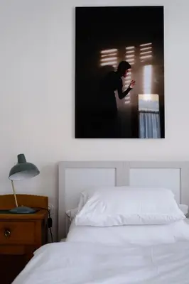a bedroom with a white bed and a picture of a woman at 1477 Reichhalter, a Member of Design Hotels in Lana