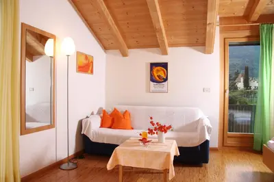 a bedroom with a bed with orange pillows and a table at Ferienwohnungen grazia dei in Lagundo