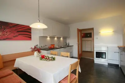 a kitchen and dining room with a white table and chairs at Ferienwohnungen grazia dei in Lagundo