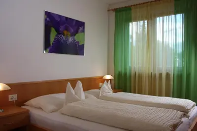 two beds in a bedroom with a green curtain at Ferienwohnungen grazia dei in Lagundo
