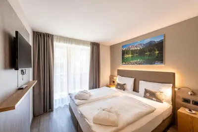 a bedroom with a large bed and a large window at Chalet Aster in Moena