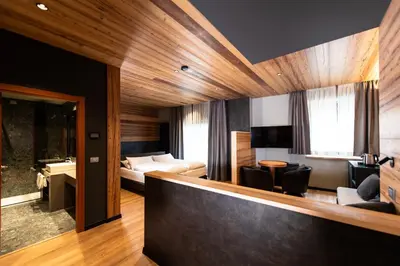 a hotel room with a bed and a living room at Sport Hotel S. Vigilio in Moena