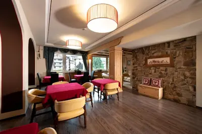 a restaurant with tables and chairs and a stone wall at Sport Hotel S. Vigilio in Moena