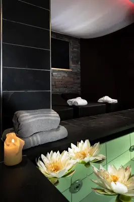 a bathroom with a table with a candle and flowers at Sport Hotel S. Vigilio in Moena