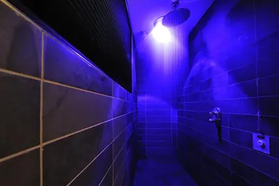 a dark bathroom with a blue light on the wall at Sport Hotel S. Vigilio in Moena